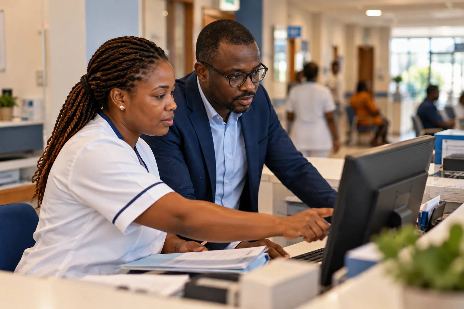 À l’accueil d’une clinique, une soignante et un gestionnaire consultent un dossier patient informatisé